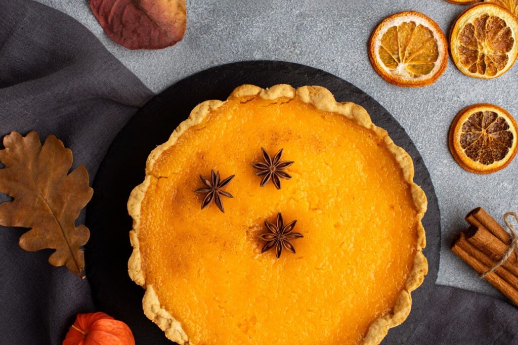 Top view of pumpkin pie and dried slices of lemon